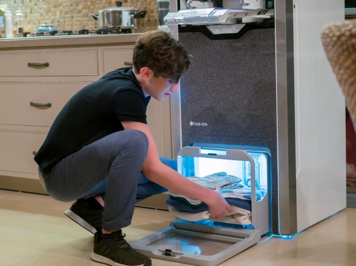 A young boy removes his impeccably folded and ironed clothes from the FoldiMate machine, offering fast, quality results. Find out how this innovative solution simplifies folding and ironing on nl.foldimateofficial.com.